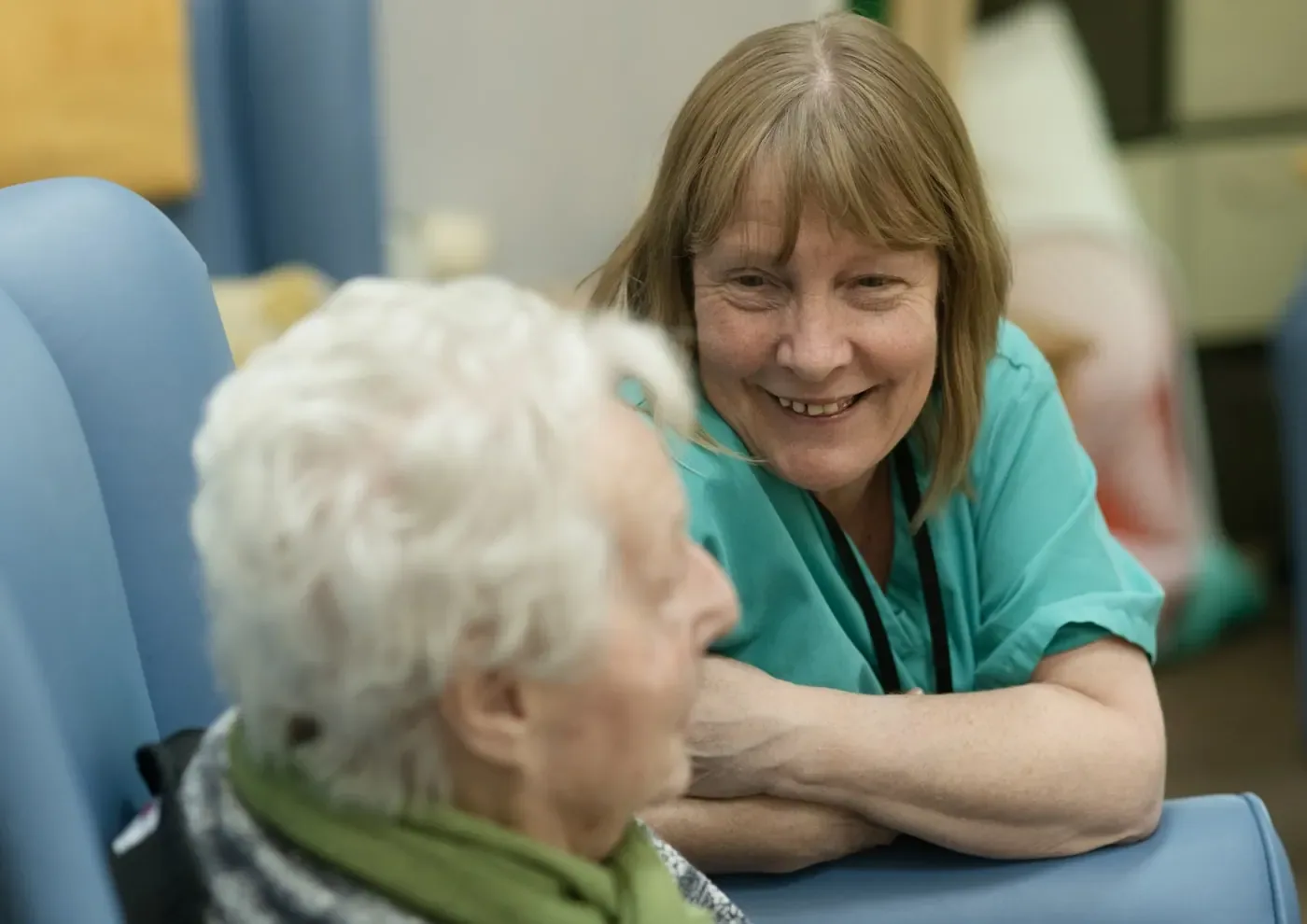 A carer sitting one to one with an older woman.